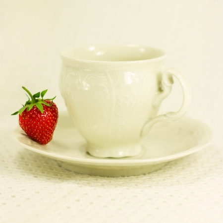 Still-life with white elegant single tea set and strawberry on a white inwrought fabric backgroundの写真素材