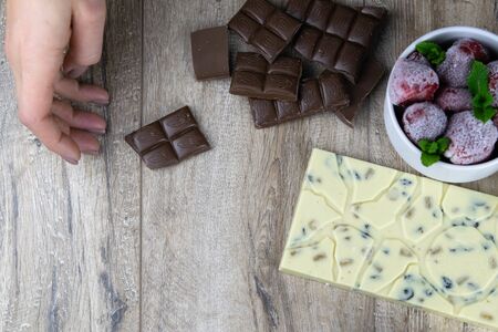 broken chocolate bar with nuts, dried strawberries and raspberries on wooden backgroundの写真素材