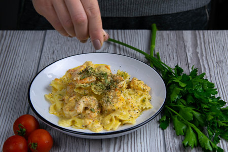 Italian pasta in a creamy sauce with shrimp on a plate sprinkled with spices, top view. Pasta in the...