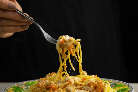 The womans hand is sprinkled with spices of sgeti bolognese plate stands on a beautiful wood background.の写真素材