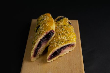 Freshly prepared puff pastry with cherry and sesame seeds close-up in a black background. Details The concept of home baking, breakfast, snack.の写真素材