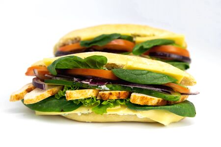 Italian ciabatta panini sandwich with chicken, cheese, tomatoes, avocado, lettuce. Isolated on white backgroundの写真素材