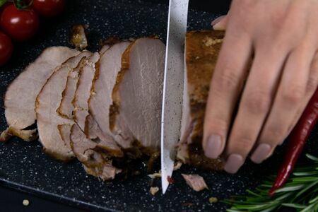 Slicing juicy beef steak by knife in women hands closeup. Food cooking concept. Dark black backgroundの写真素材
