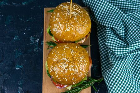 Two homemade beef burgers with mushrooms, micro greens, red onion, fried eggs and beet sauce on wooden cutting board with clear spaceの写真素材