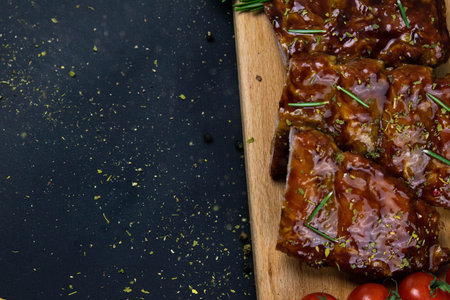 Barbecue Pork Spare Ribs as side view with basil and tomatoes and hot pepper with cracker on an old...