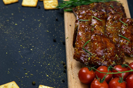 Barbecue Pork Spare Ribs as side view with basil and tomatoes and hot pepper with cracker on an old...