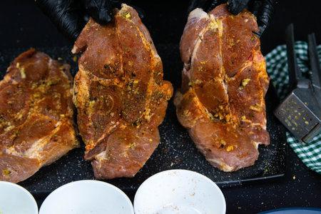 A chef in black gloves prepares a raw tenderloin. Fresh raw pork tenderloin on a wooden cutting board. Close up.の写真素材