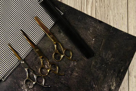 A set of scissors for haircuts and black dew on a beautiful striped towel, under a towel black...