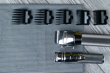 Cars for haircuts with nozzles of different sizes are laid out on a striped towel that stands on a...