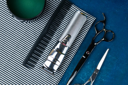 A haircut machine with scissors on a beautiful striped towel that stands on a blue background....
