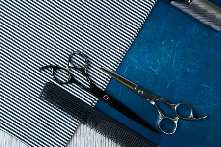 A haircut machine with scissors on a beautiful striped towel that stands on a blue background....