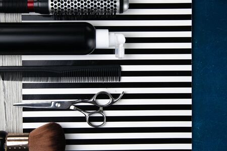 Haircut machines, nozzles of different sizes, combs and gels for styling, laid out on a beautiful black white striped background which stands on a blue background. Clear spaceの写真素材