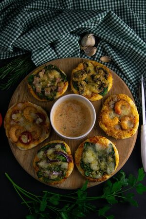 Small mini pizza and souce. Set of different mini pizzas. On a tray pizza: with shrimp, with mushrooms, with spinach and onions, with bacon, with paperoni, with tomatoes. Top viewsの写真素材
