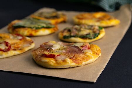 Small mini pizza. Set of different mini pizzas. Pizza on craft paper: with shrimp, with mushrooms, with spinach and onions, with bacon, with paperoni, with tomatoes. Top viewsの写真素材