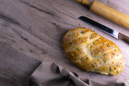 A loaf of bread under a towel on the table with a glass of milk and butter. Top views