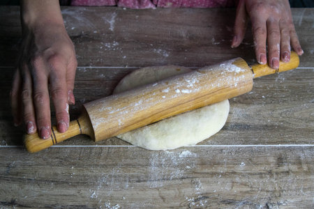 Women's hands mix the dough on a wooden table. Preparing bread for baking. Front views
