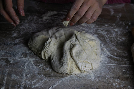 Women's hands mix the dough on a wooden table. Preparing bread for baking. Front views