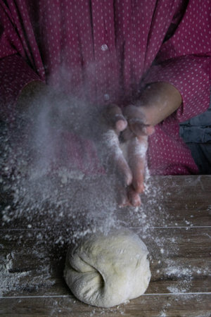 A woman claps her hands around the go splashes of flour. Process of preparation of dough for baking...