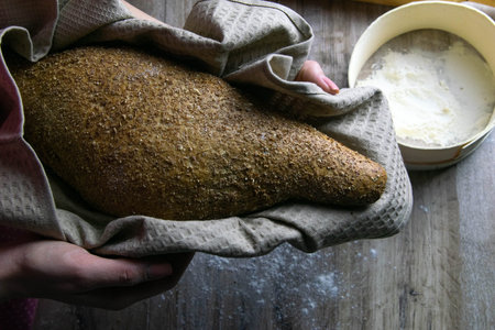 Closeup of fresh rustsic bread in a woman's hand. Top viewsの写真素材