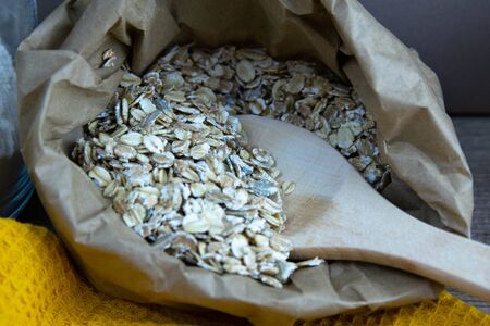 Craft bag filled with oatmeal, inside a wooden spoon. Front viewsの写真素材