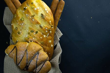 Different kinds of fresh bread with grain on black rustic background. Top views with clear spaceの写真素材