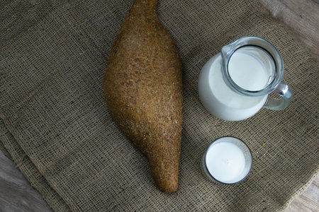 A loaf of bread with milk and butter dough stands on a craft linen bag. Top view with clear spaceの写真素材