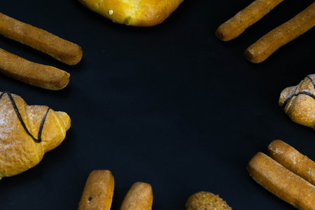 Different types of fresh bread with grain on a black rustic background. the bread stands around. Top...
