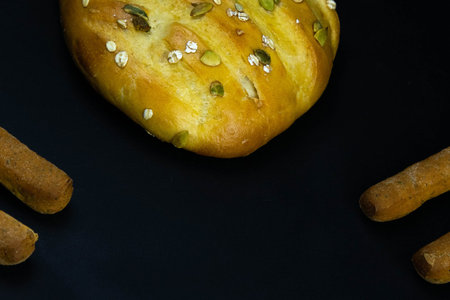 Different types of fresh bread with grain on a black rustic background. the bread stands around on...