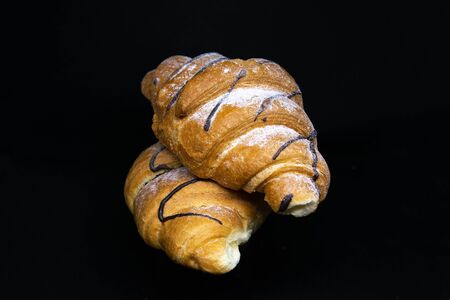 Croissant with chocolate isolated on a black background. Front viewsの写真素材