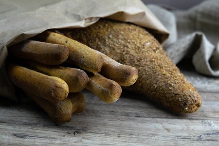 Different types of fresh bread in a craft bag stand on a wooden table. Top viewsの写真素材