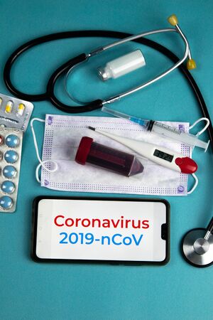 Coronavirus 2019-nCoV. Corona virus outbreaking. Epidemic virus Respiratory Syndrome.Blood tube, Phonendoscope, Mask, syringe, tablets and gloves With a phone that says coronavirus 2019 nCoVの写真素材