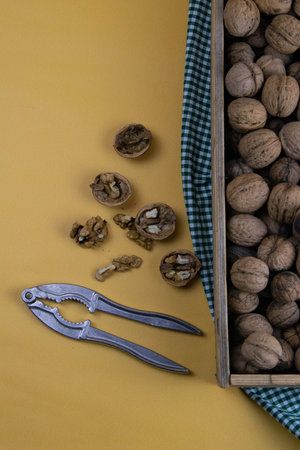 Whole walnuts in shells in a box, walnuts kernels. next to the box is a nut crush. Top views with...