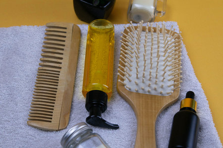 Cosmetics for hair care with jojoba, argan or coconut oil. Oil bottles and combs on a towel that...