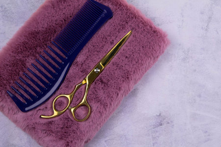 A set of scissors for a haircut and a black dew on a beautiful pink notebook that stands on a...