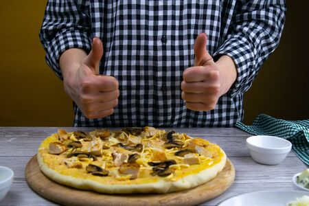 Woman lays mushrooms on a dough for drinking. Fresh original italian raw pizza. Preparatory process.の写真素材