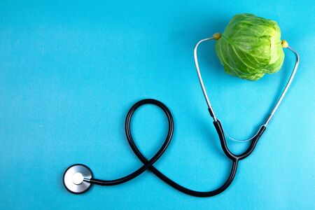 Green young cabbage with a stethoscope isolated on blue background. Healthcare And Medicine. Top views with clear spaceの写真素材