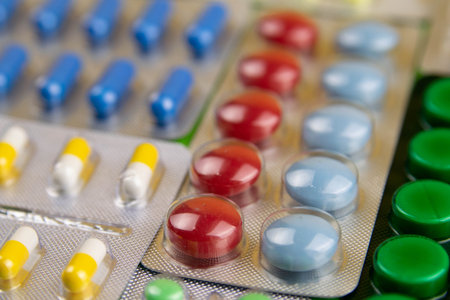 Pills of different colours lay on blue background. Colorful antibacterials pills, capsules of...