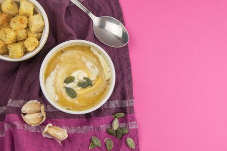 Pea soup with pumpkin seeds, next to greens and croutons with garlic stand on a purple towel. Top views with clear spaceの写真素材
