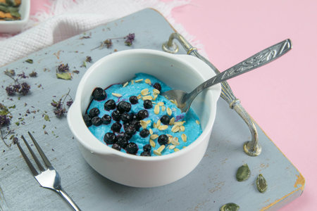 Cottage cheese with jam, fresh blueberries and pumpkin seeds in a ceramic bowl, closeup. Tasty and...