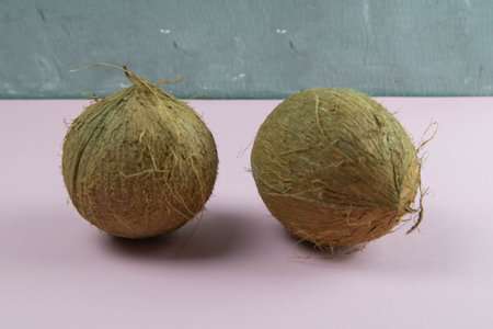 Whole coconut on white fabric which stands on a pink background.