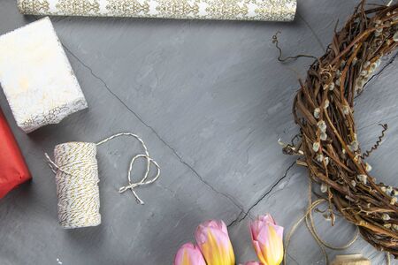 Preparing for the packaging of gifts, on the table laid out red and white wrapping paper, threads of different colors for winding, scissors and tulips.の写真素材