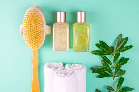 Three towels, body care oils, a green branch and a brush stand on a green background. The concept of spa treatments, a healthy body.の写真素材