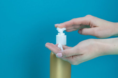 Women's hands put soap on their hands. The concept of hand sanitization on a blue background. Front...