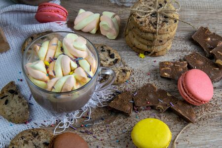 Cocoa with marshmallows and chocolate oven, muffins and chocolate slices stand on wooden table.の写真素材