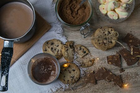 Cocoa with marshmallows and chocolate oven and slices of chocolate stands on a wooden table.の写真素材
