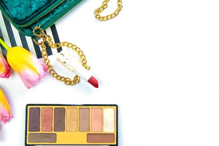 Tulips with green women's clutch, pallet with shadows and women's cosmetics on a white background.の写真素材