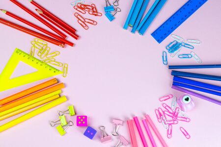 Multi-colored pencils rulers, pens, pencils and scissors and stationery stand on a pink background.の写真素材