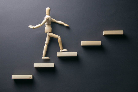 Wooden man walk up the career stairs. Ladder made with wooden bricks. Mannequin on top of...