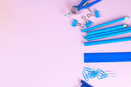 Multi-colored blue pencils rulers, pens, pencils and scissors and stationery stand on a pink...