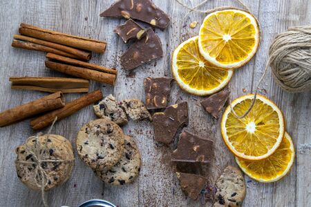 Dried oranges, chocolate slices, chocolate biscuits and cinnamon on a wooden table.の写真素材